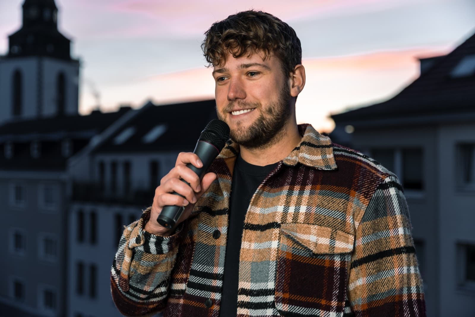 Niklas moderiert mit Mikrofon auf der Bühne eines Sportevents